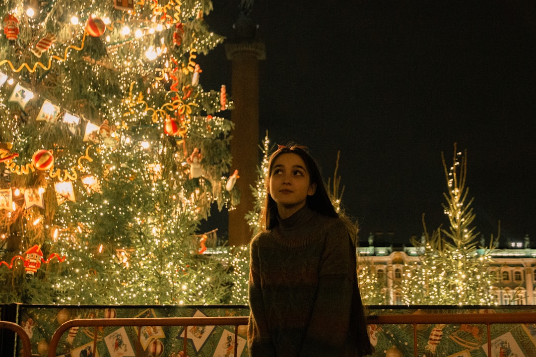 woman in brown coat standing near christmas tree