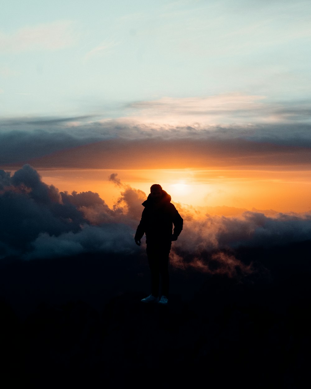man in black jacket standing on top of mountain during sunset