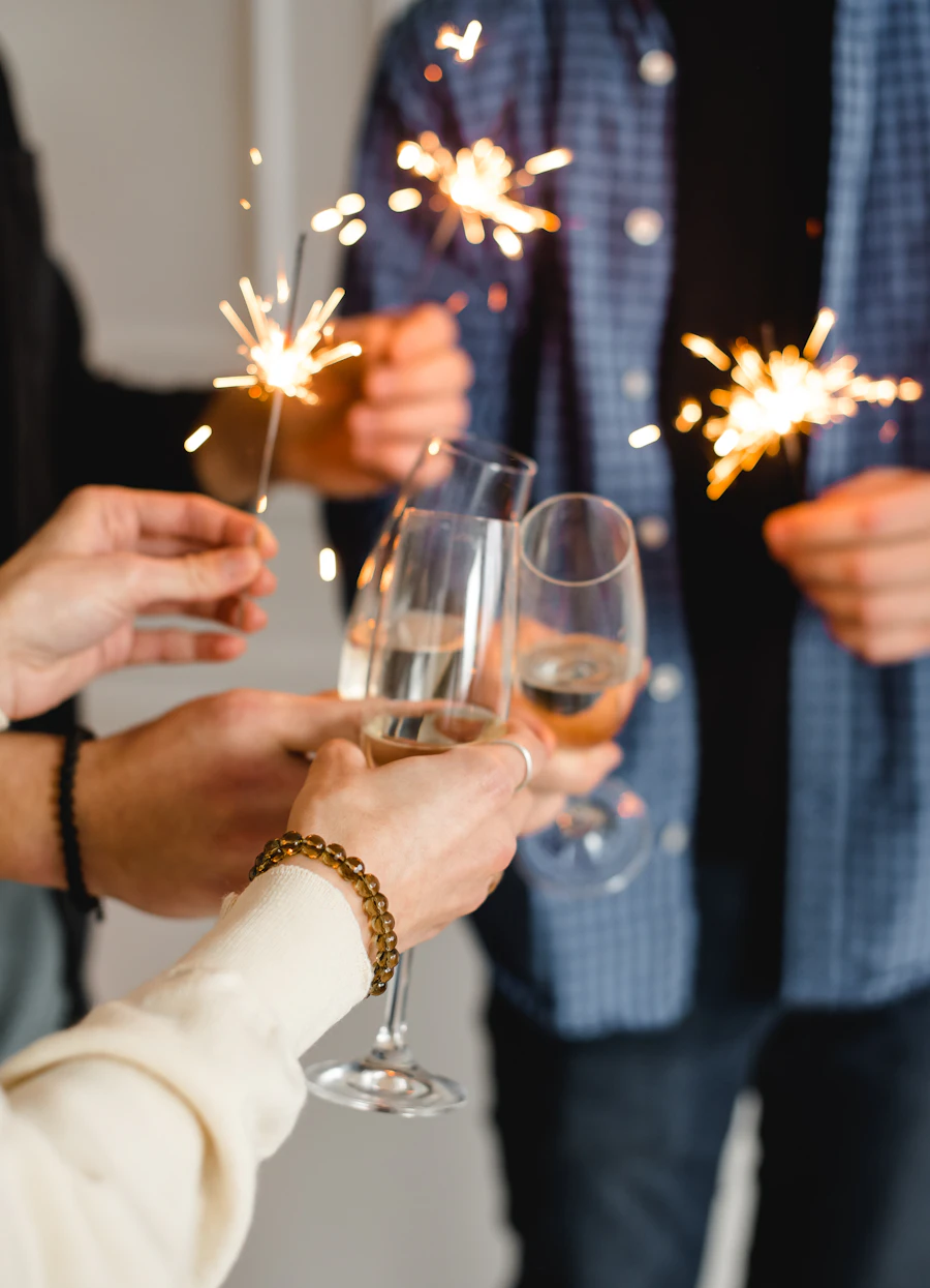 Friends toasting with champagne and sparklers, one wrist wearing a gold chain bracelet