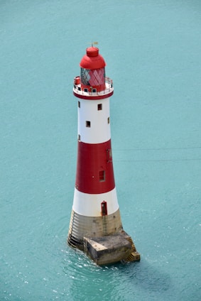 red and white lighthouse beside green wall
