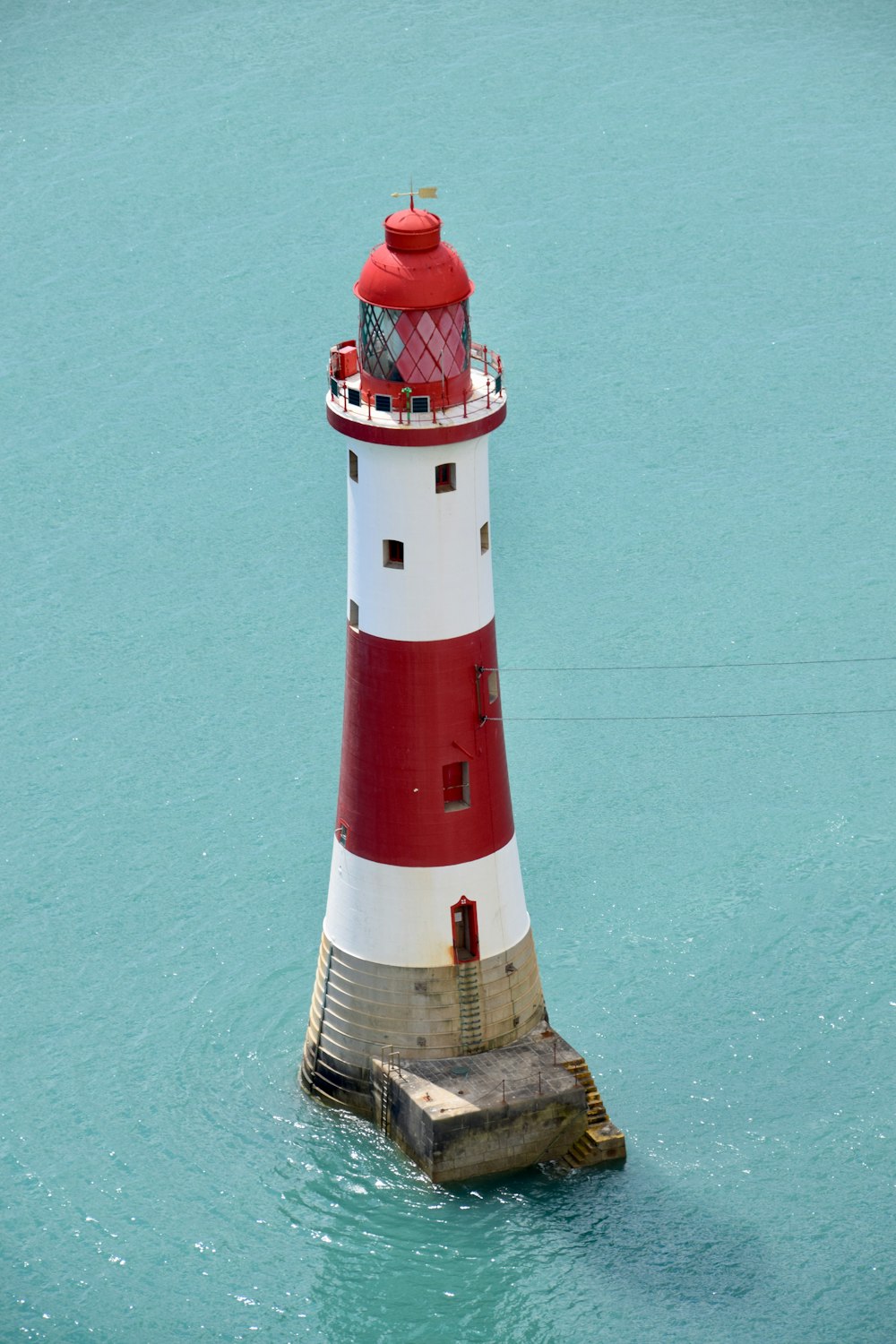 Phare rouge et blanc à côté du mur vert