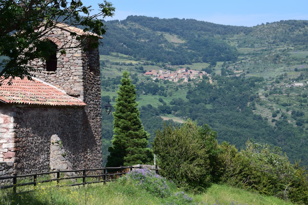 Braunes Backsteinhaus auf grünem Grasfeld in der Nähe von grünen Bäumen tagsüber