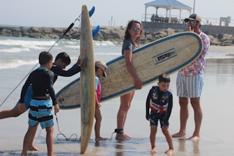 man in black t-shirt holding brown surfboard