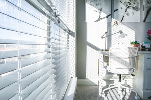 Office space with custom wooden blinds casting gentle shadows on a tidy desk.