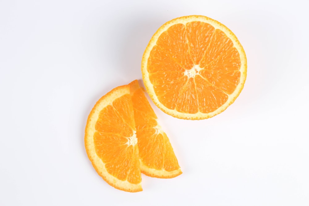 fruta naranja en rodajas sobre superficie blanca
