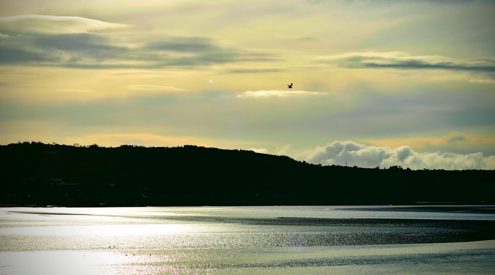 silhouette of mountain and body of water during sunset