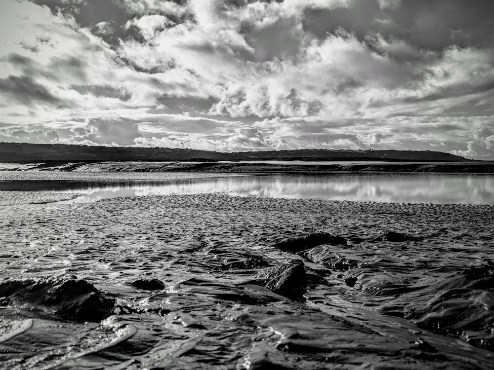 grayscale photo of body of water under cloudy sky