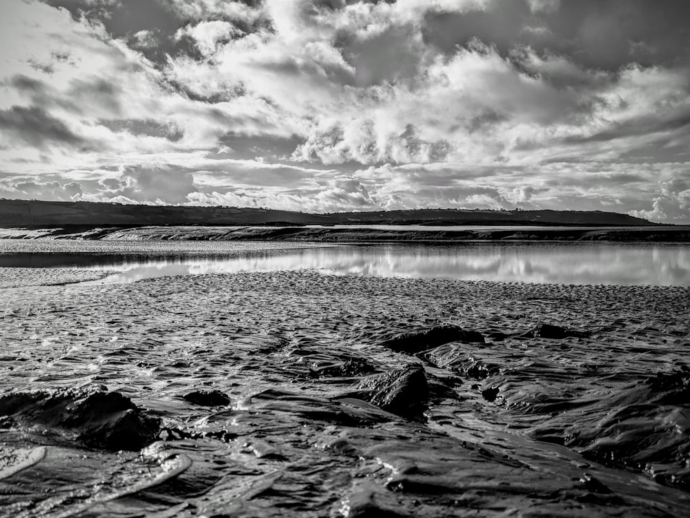 Photo en niveaux de gris d’un plan d’eau sous un ciel nuageux