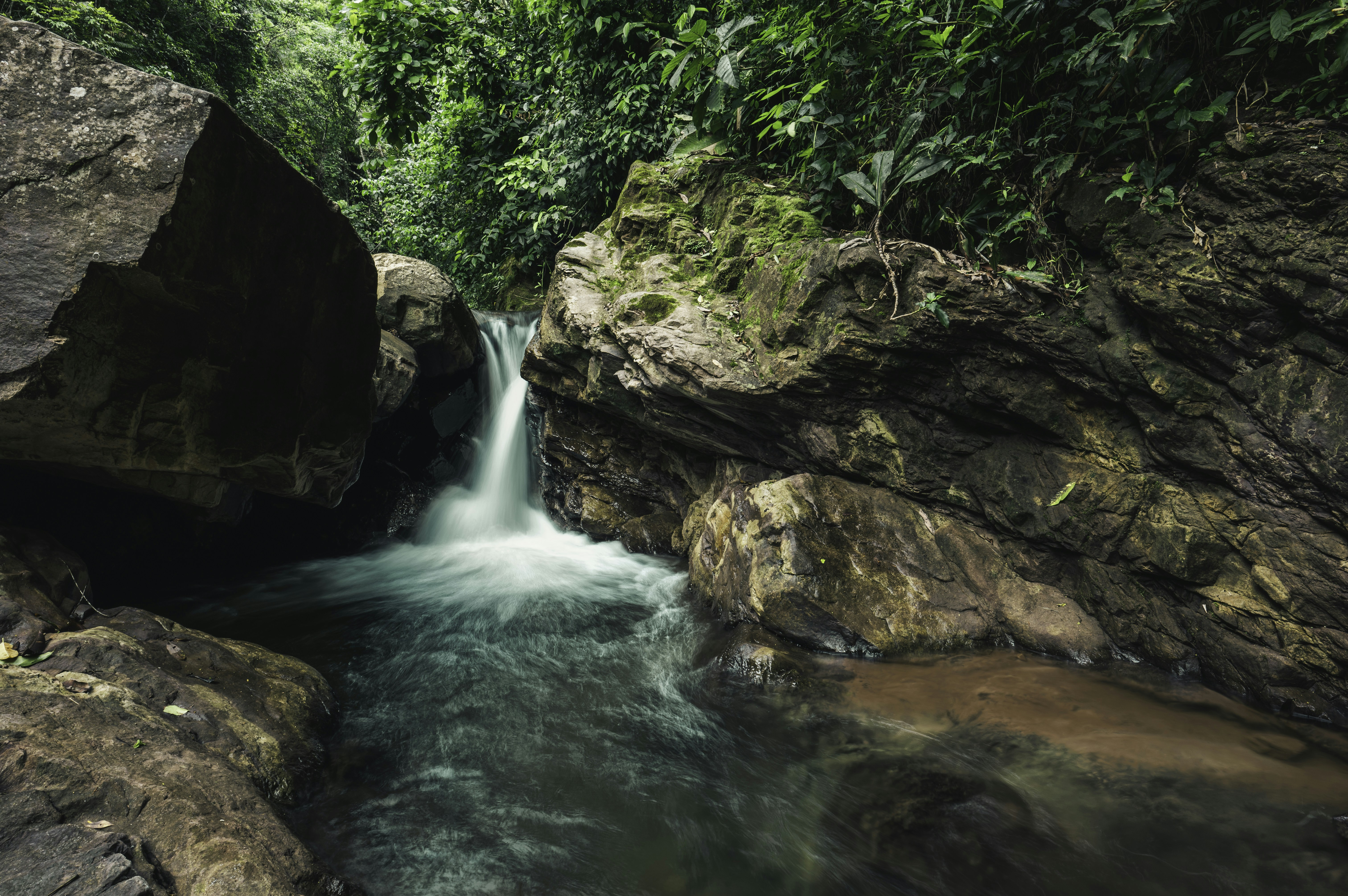 brown and green rock formation beside river during daytime, 