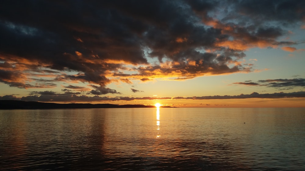 body of water under cloudy sky during sunset