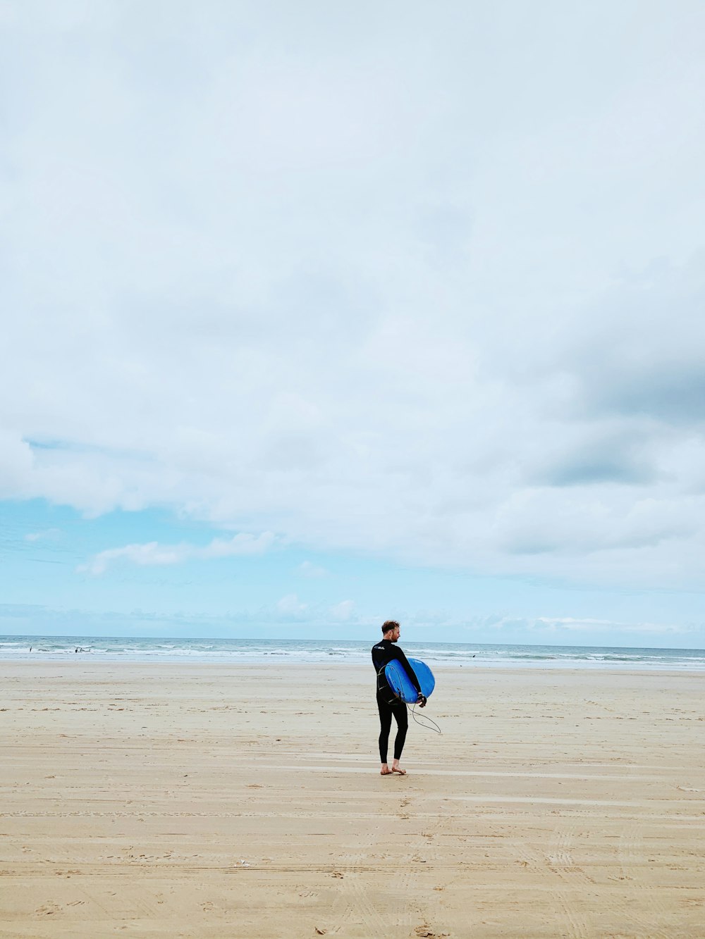 woman in blue jacket walking on beach during daytime