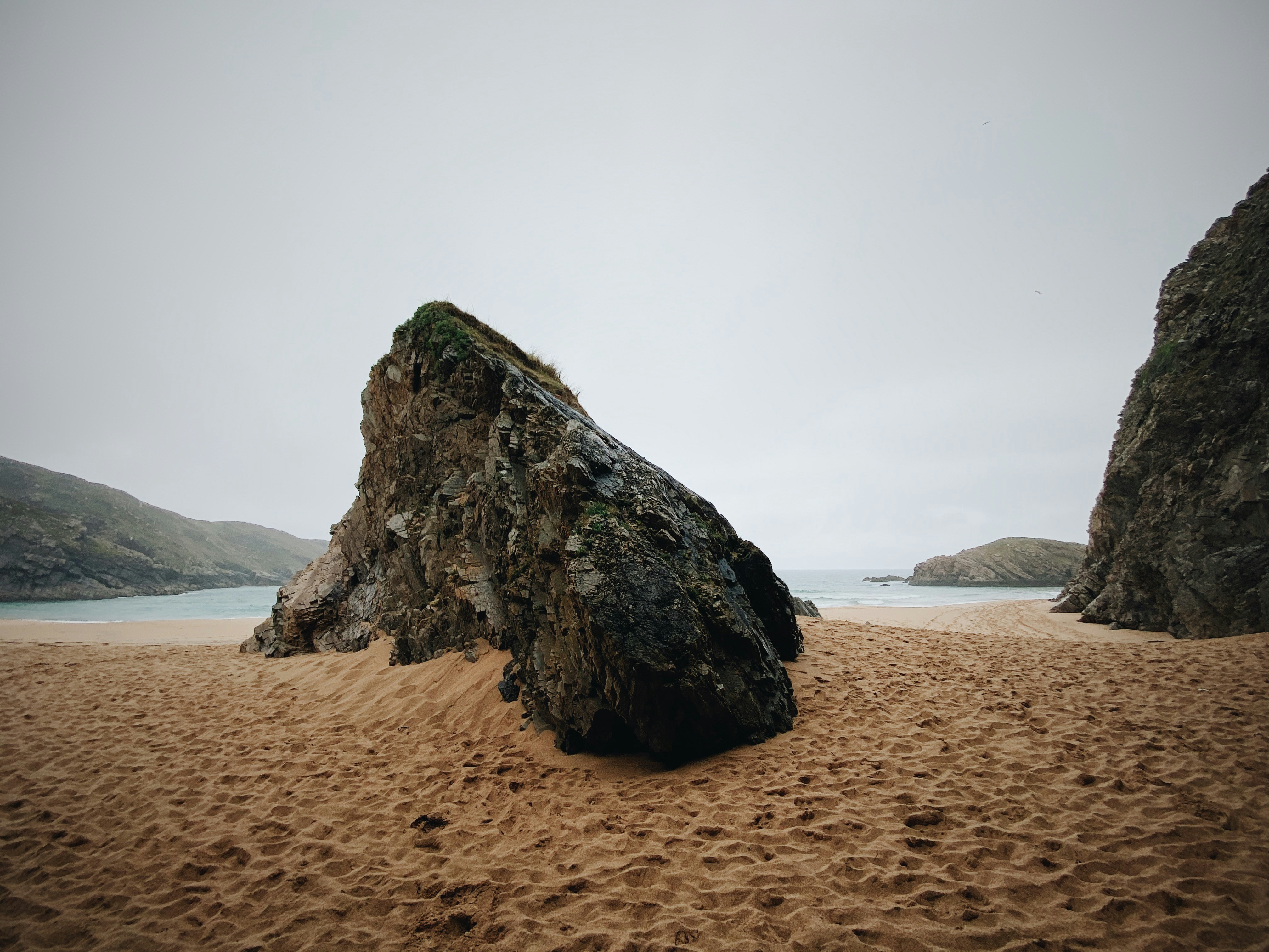 brown rock formation on brown sand near body of water during daytime, 