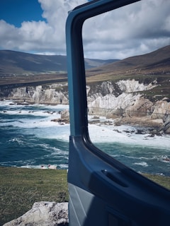 blue and white boat on water near brown rock formation during daytime