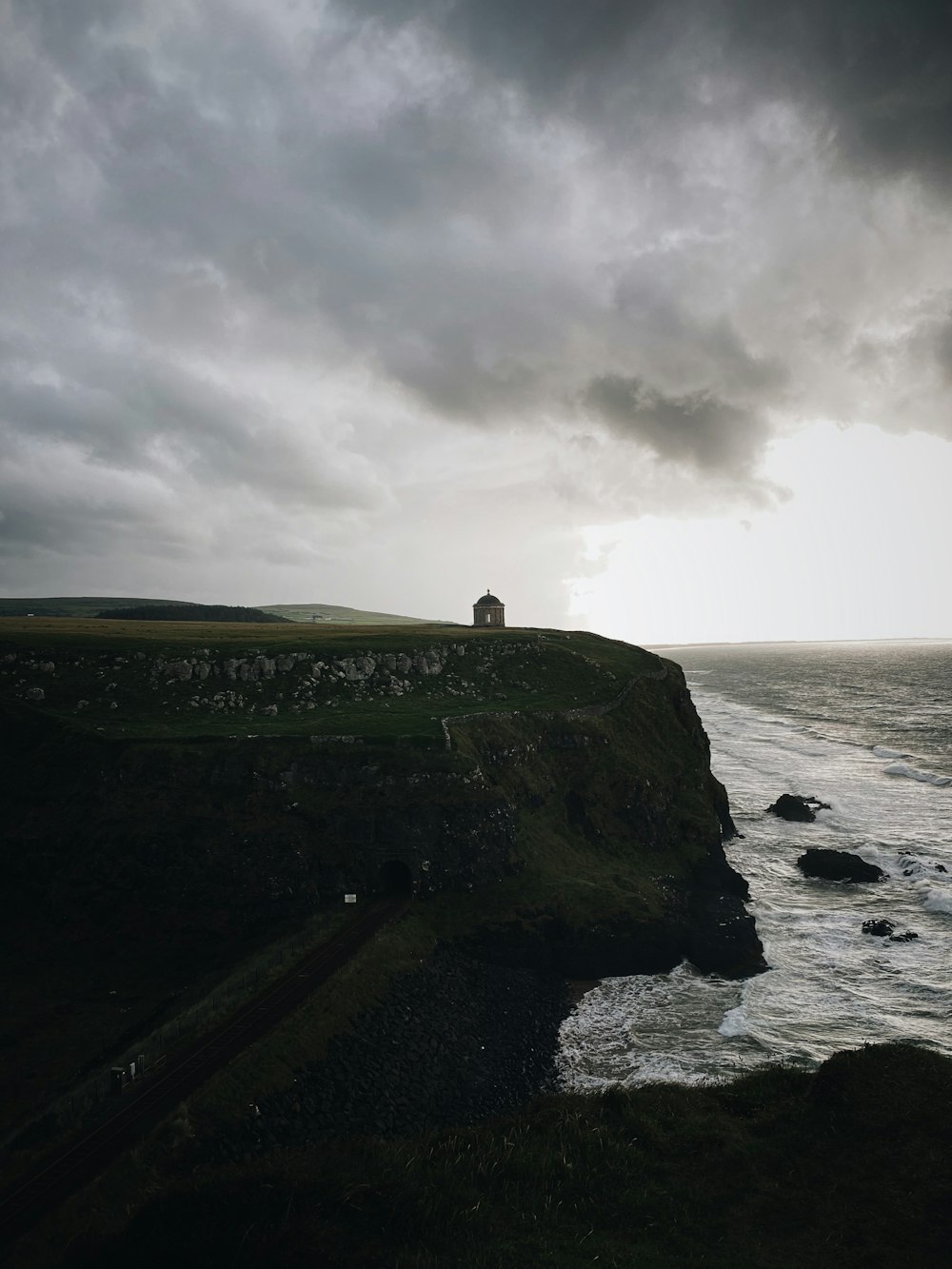 person standing on rock formation near sea under cloudy sky during daytime