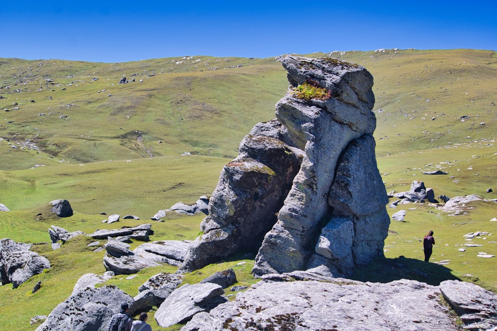 gray rock formation on green grass field under blue sky during daytime