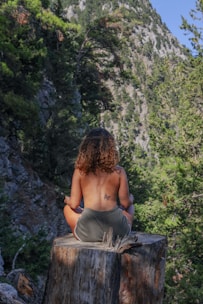a woman sitting on top of a tree stump