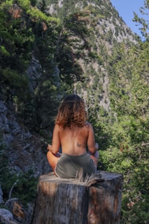 a woman sitting on top of a tree stump