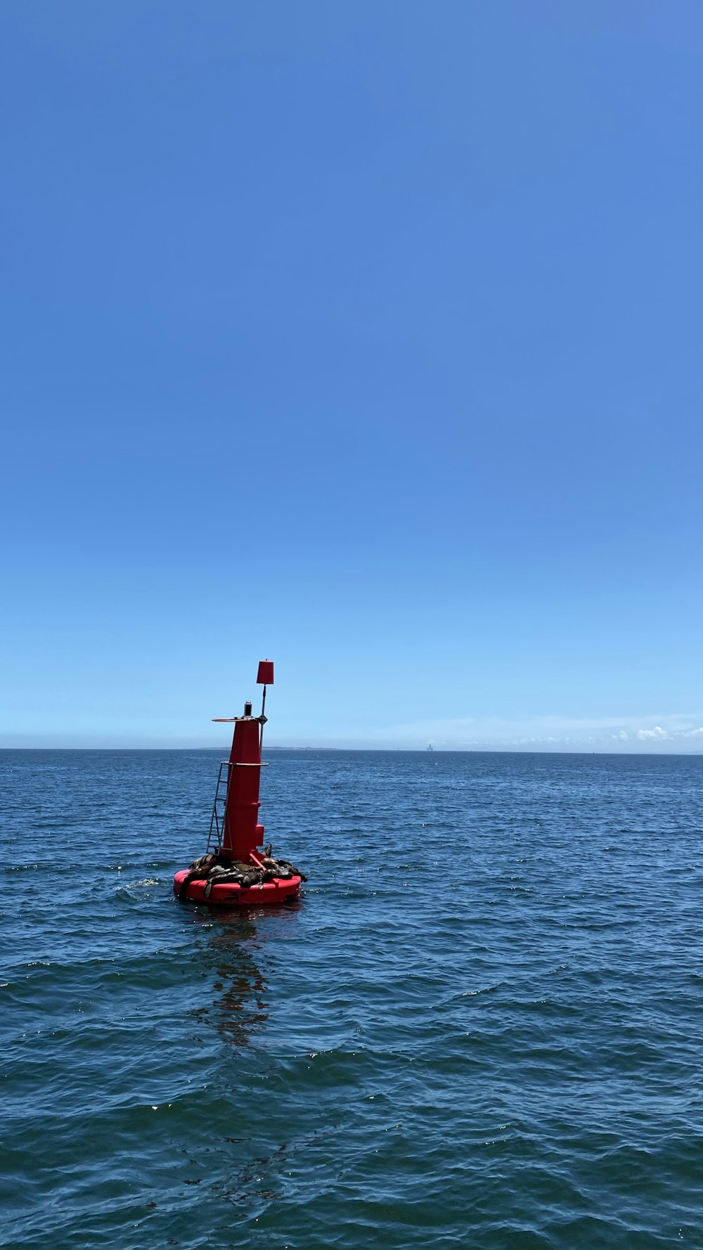 red and white light post on sea under blue sky during daytime