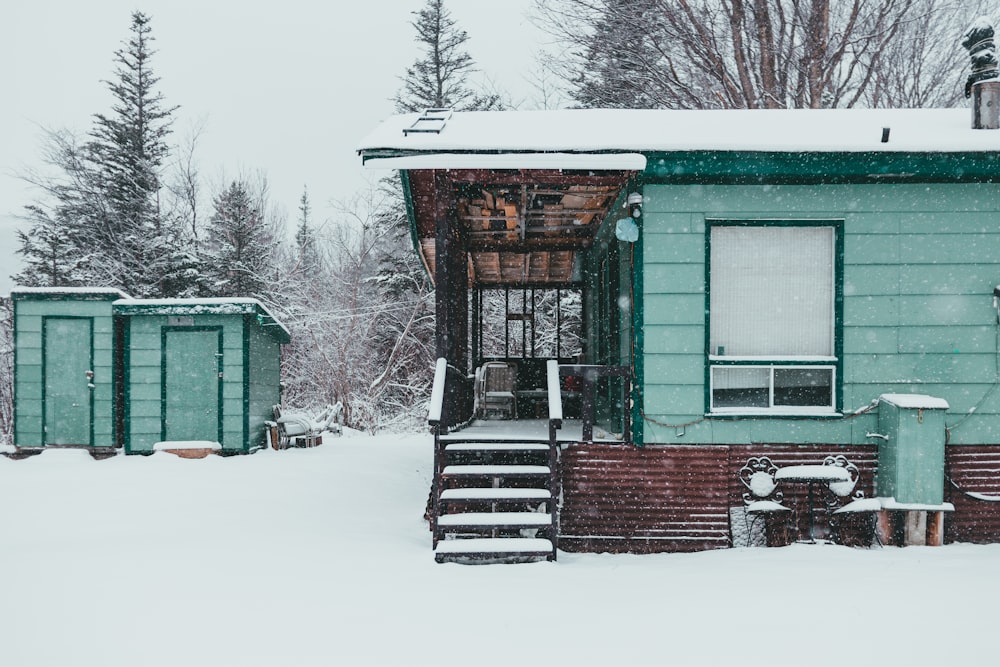 casa de madeira verde e marrom coberta de neve durante o dia