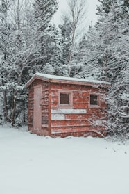 A rustic wooden shed at the winter market with snow gently falling around it.
