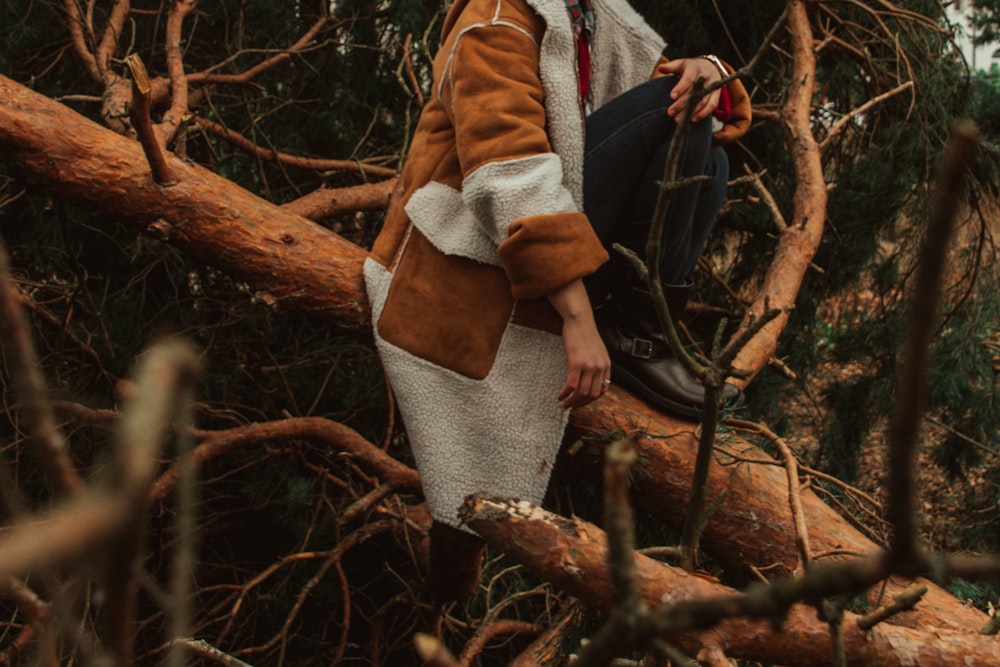 woman in brown coat and gray skirt standing on tree branch