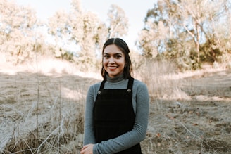 A smiling young woman demonstrating smart farming technology to a small group outdoors.