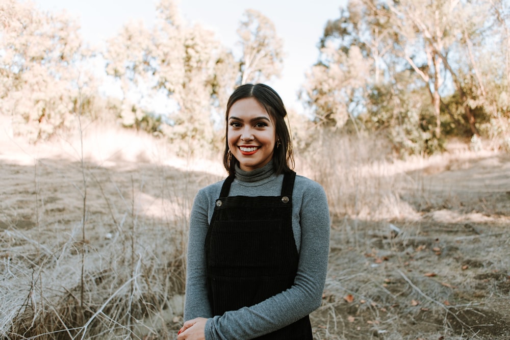 woman in black long sleeve shirt and gray pants standing on brown grass field during daytime