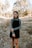woman in gray long sleeve shirt and black skirt standing on brown dried leaves during daytime