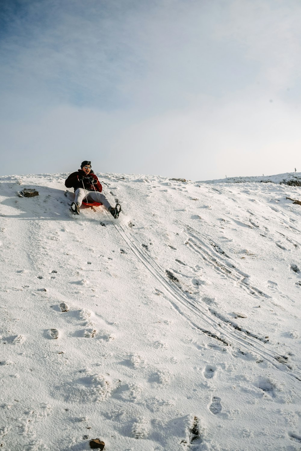 person in black jacket and black pants sitting on snow covered ground during daytime