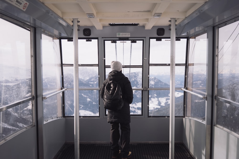 man in black jacket standing near glass window