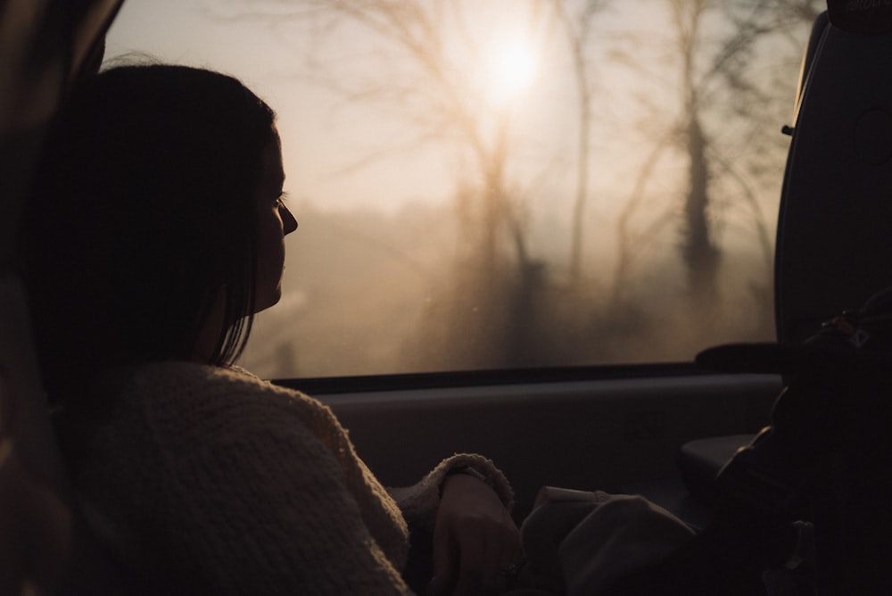 woman in white sweater sitting on car seat during daytime