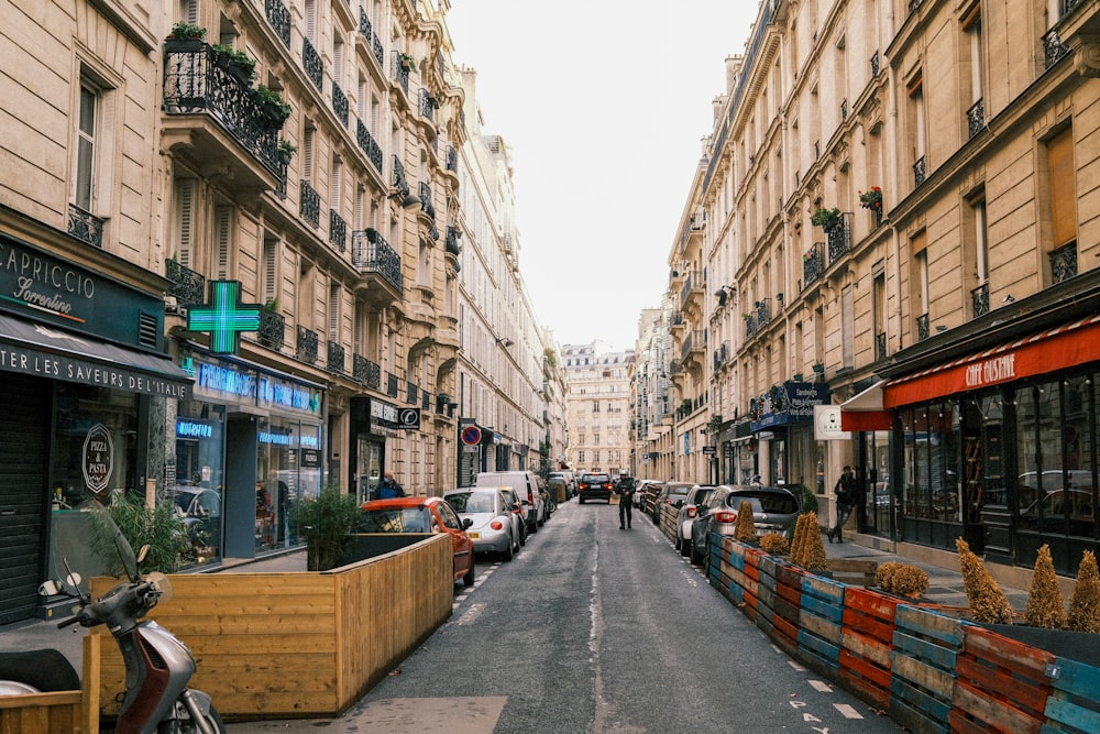 cars parked on the side of the road in between buildings during daytime