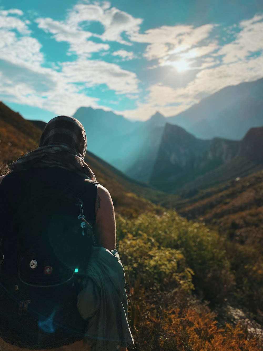 man in black t-shirt and green shorts sitting on rock looking at mountains during daytime