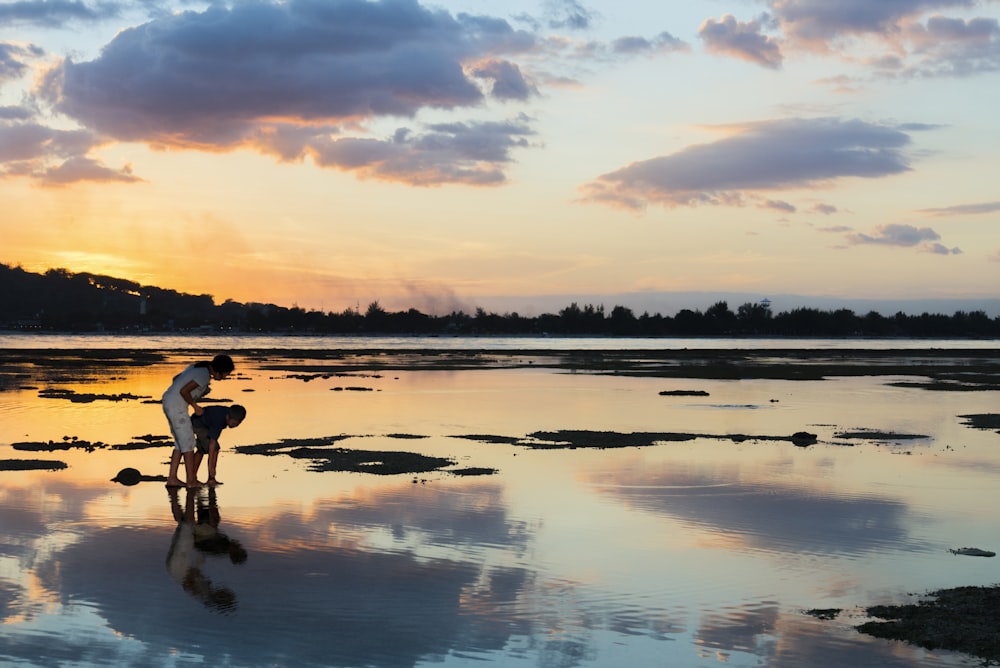 2 men and woman standing on water during sunset