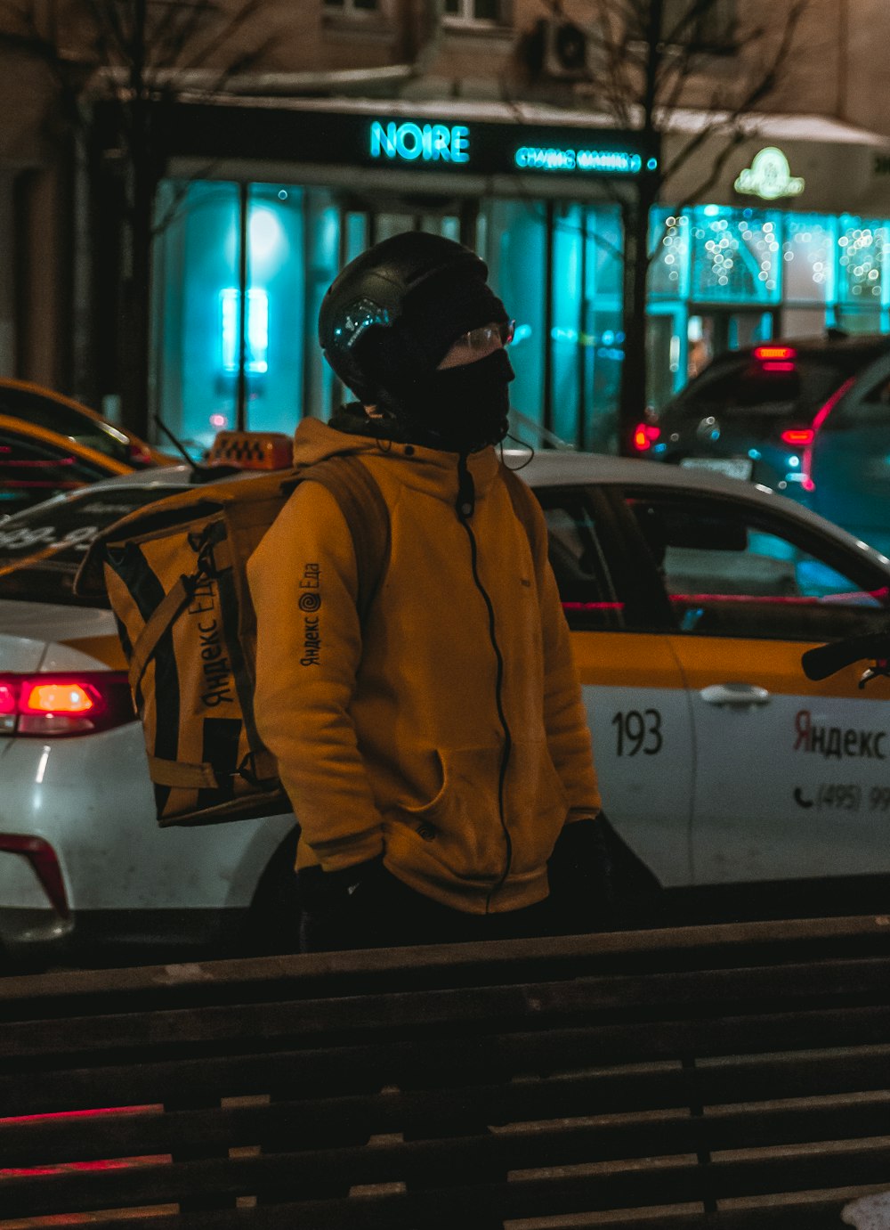 man in brown jacket and black cap standing beside white car during daytime