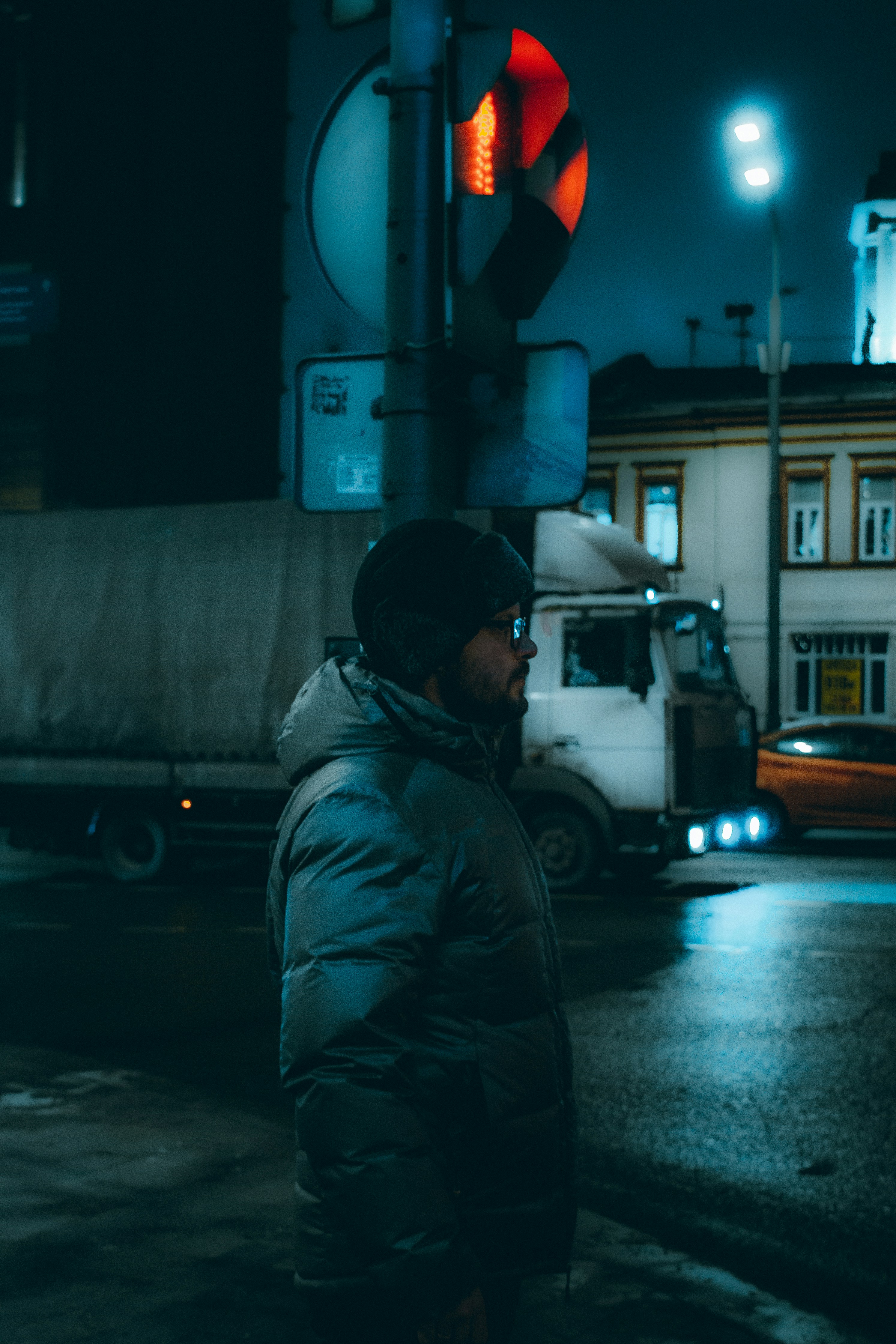 man in gray jacket standing near white truck during night time