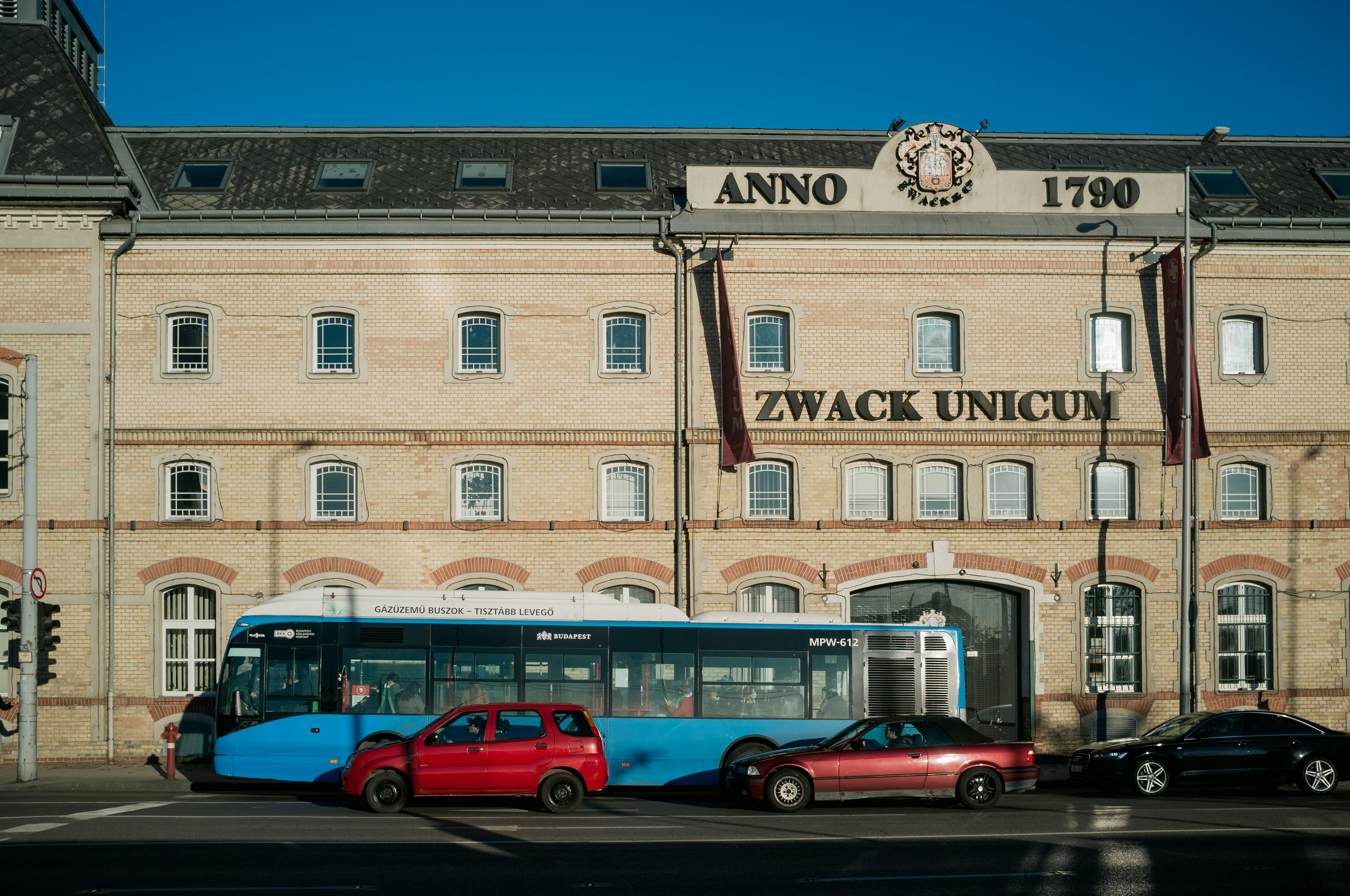 red and green bus in front of brown concrete building during daytime