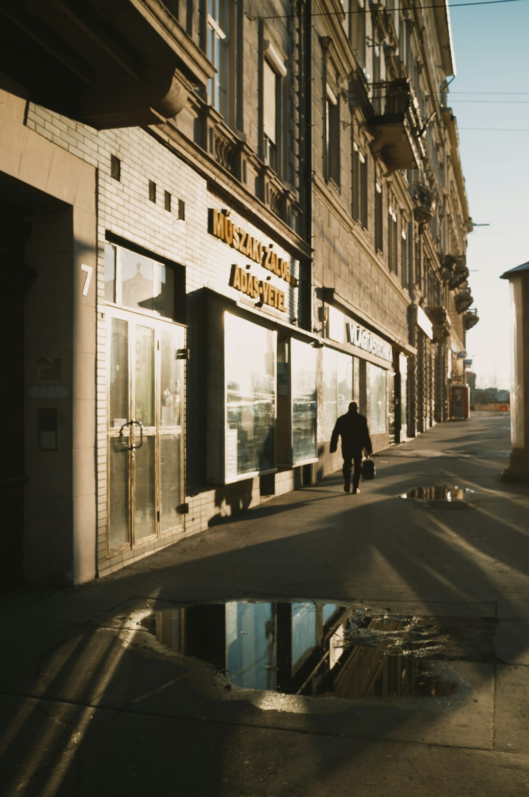 man in black jacket walking on sidewalk during daytime