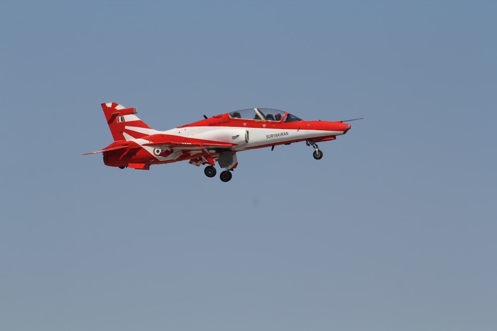 red and white jet plane in mid air