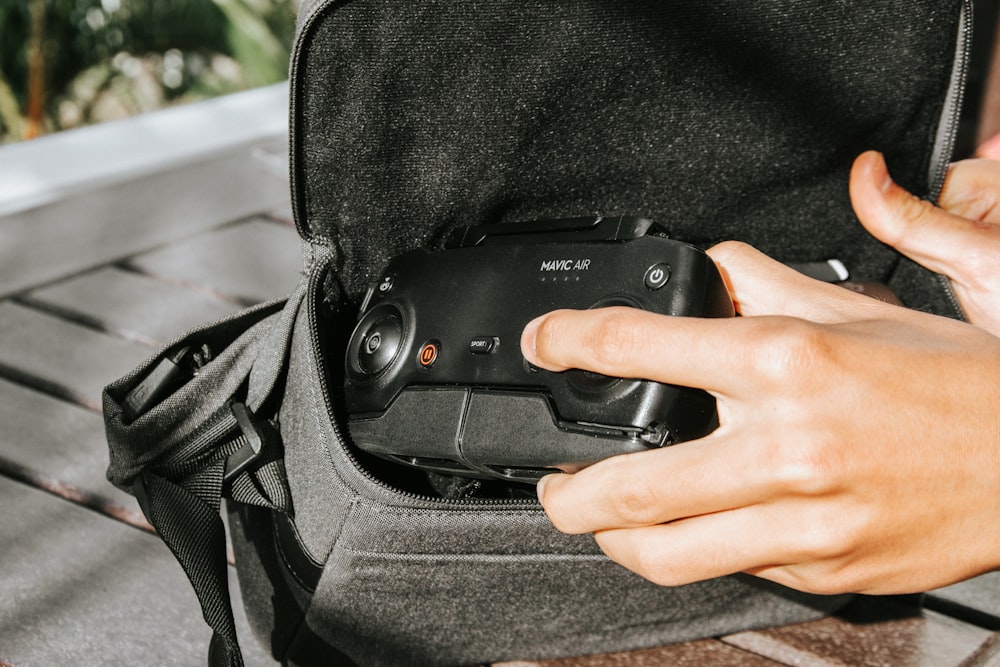 person holding black smartphone on black backpack