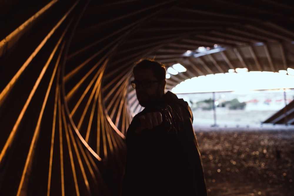 man in black jacket standing near brown wall during daytime