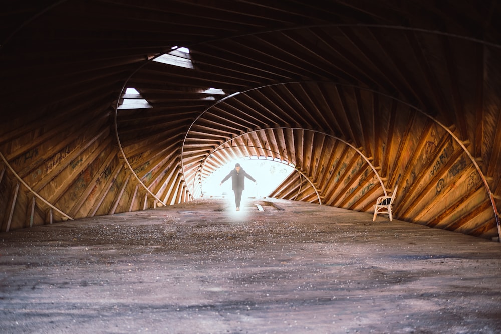 person in black jacket walking on tunnel