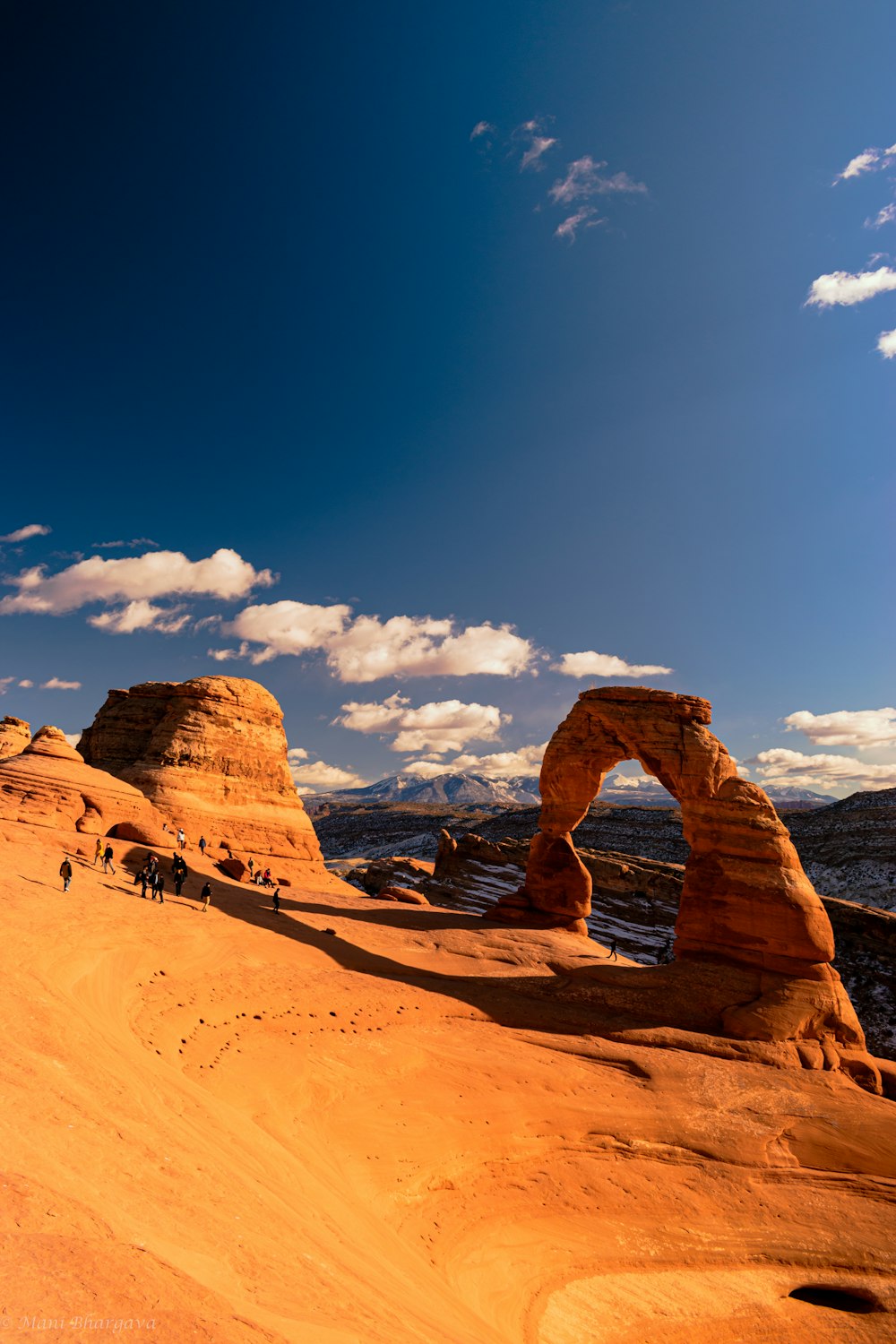 man in black jacket and pants sitting on brown rock formation under blue sky during daytime