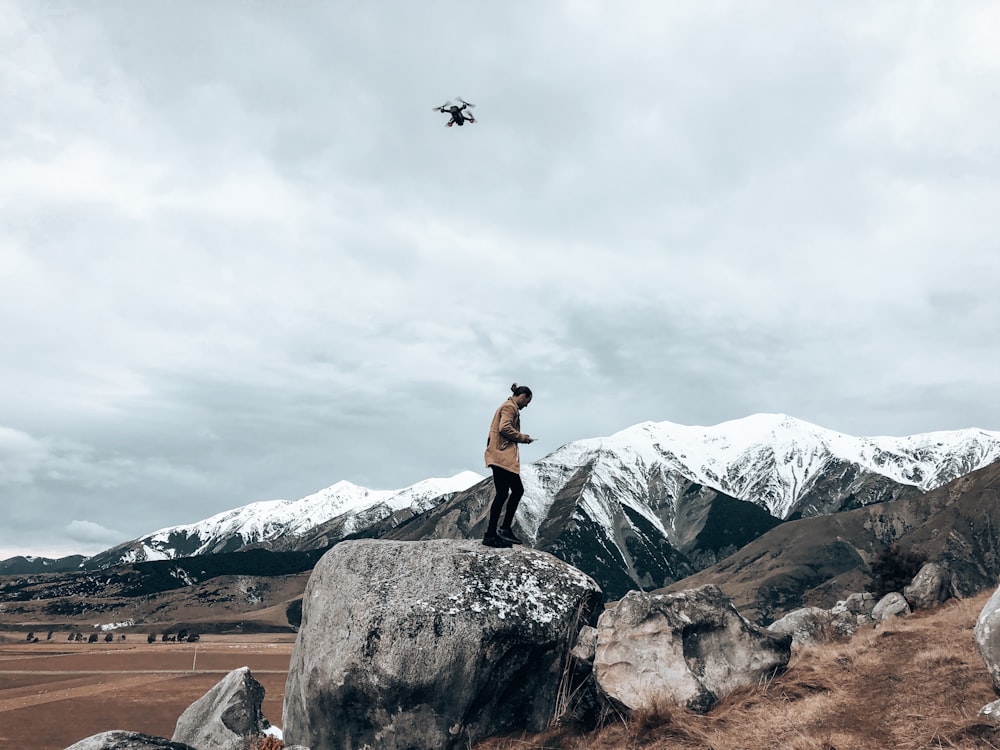 man in black tank top standing on rock formation during daytime