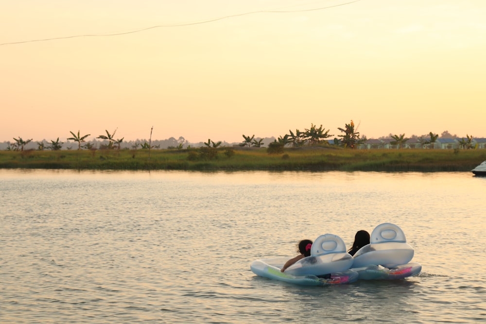 2 people riding on white kayak on body of water during daytime