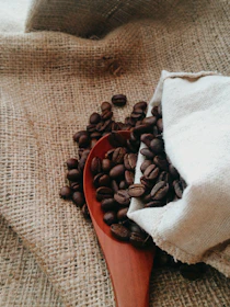 Artisan ceramic spoons resting on a cream-colored linen cloth beside coffee beans.