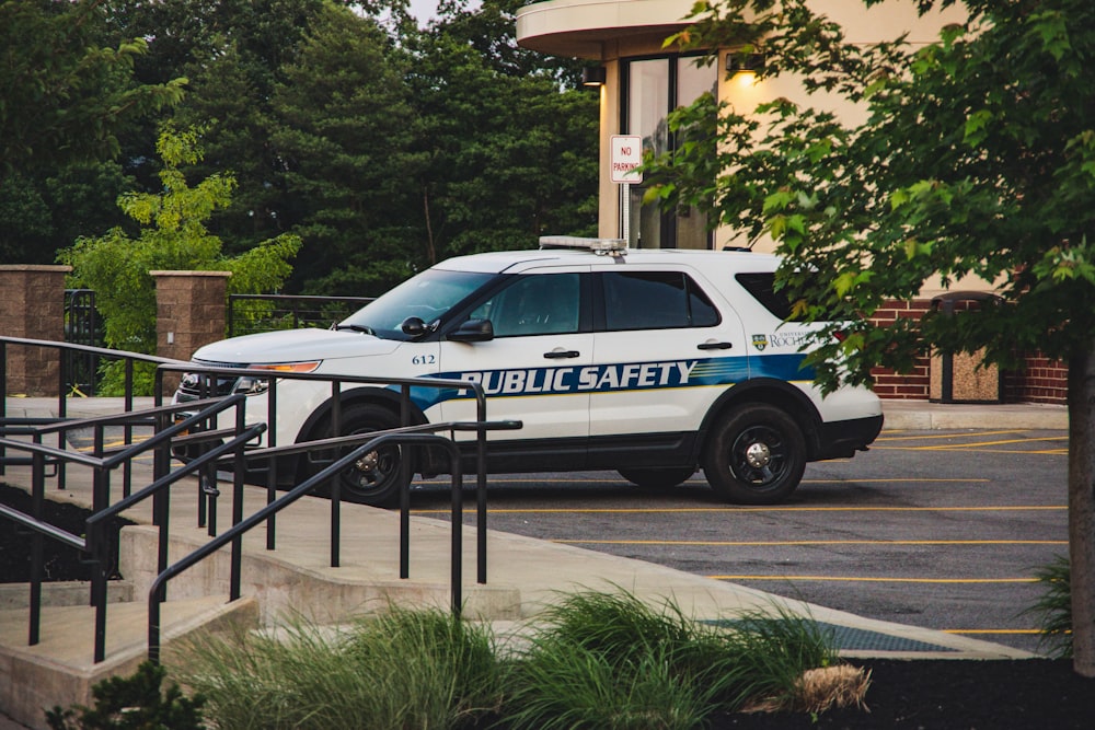 white and blue police car parked near green trees during daytime