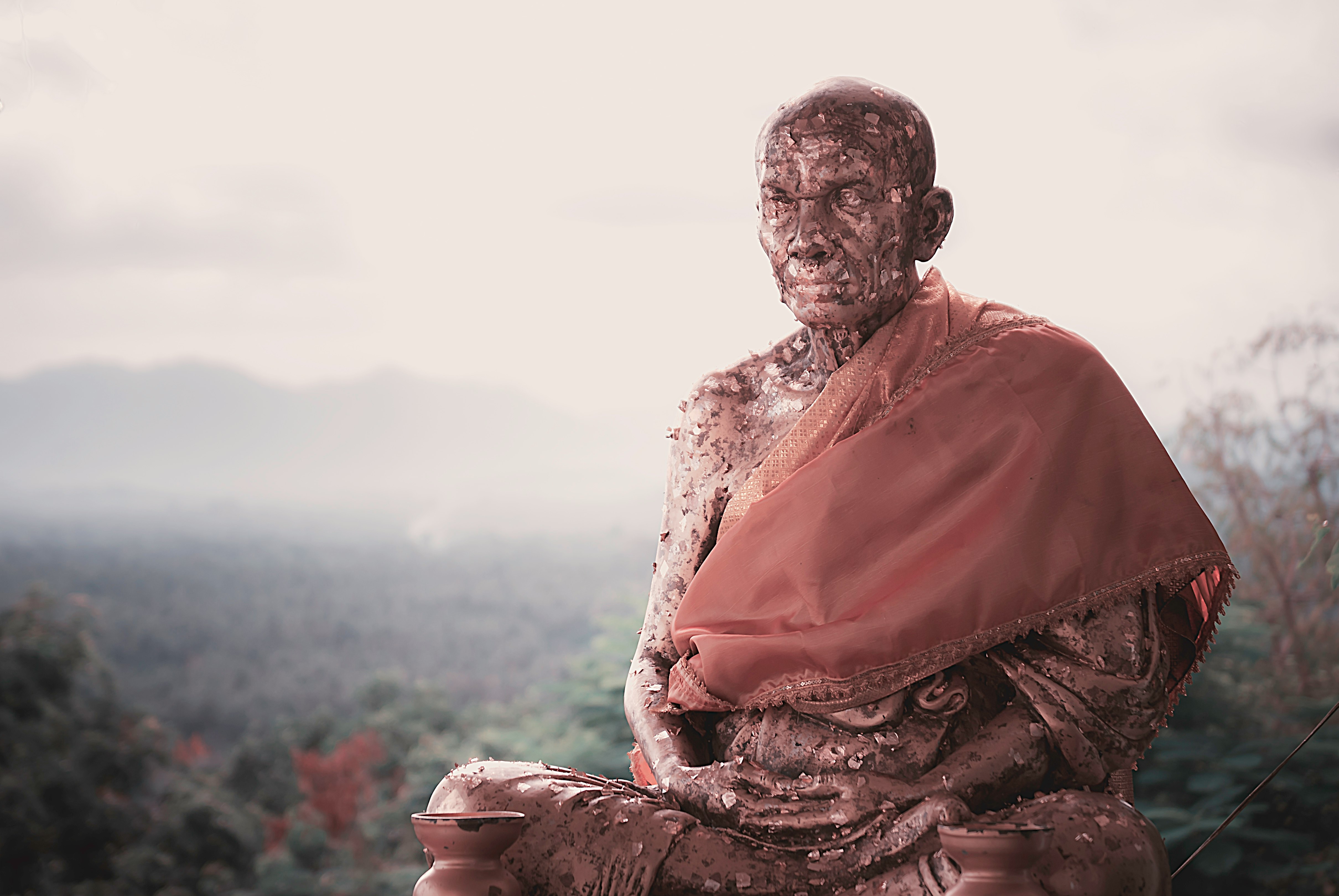 man in red robe sitting on rock during daytime