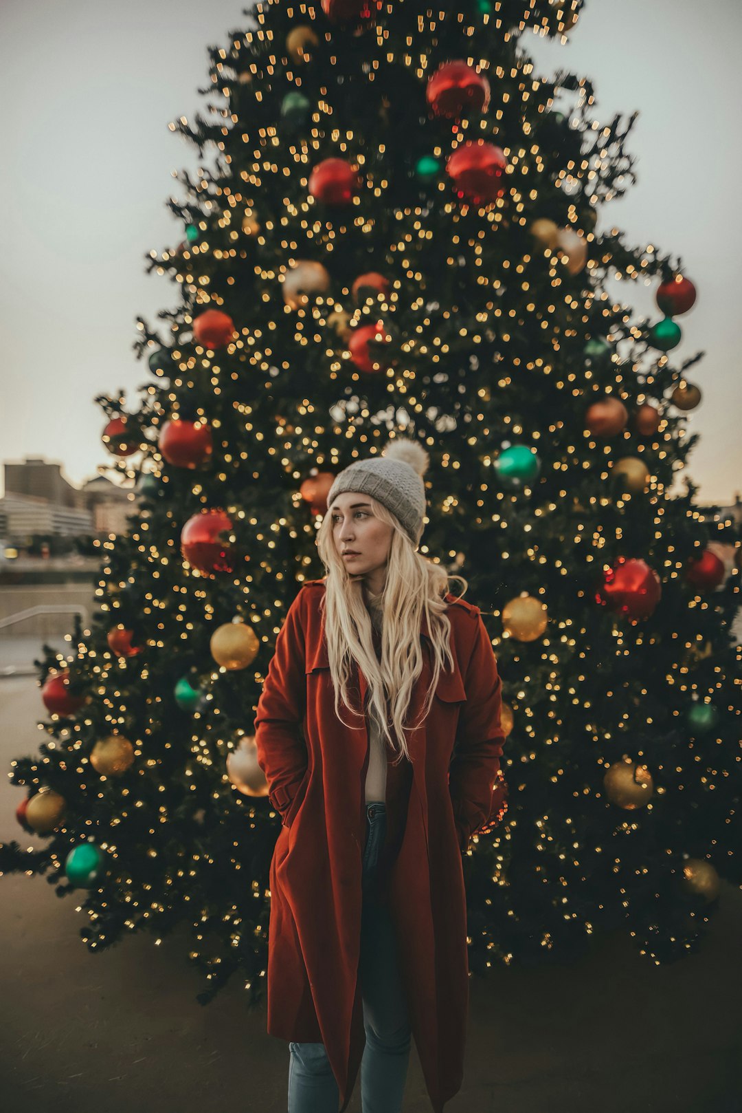 woman in red coat standing near christmas tree