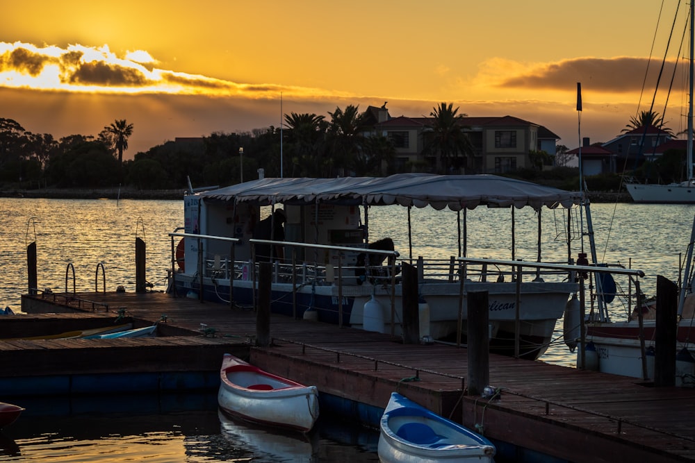 white and blue boat on dock during sunset